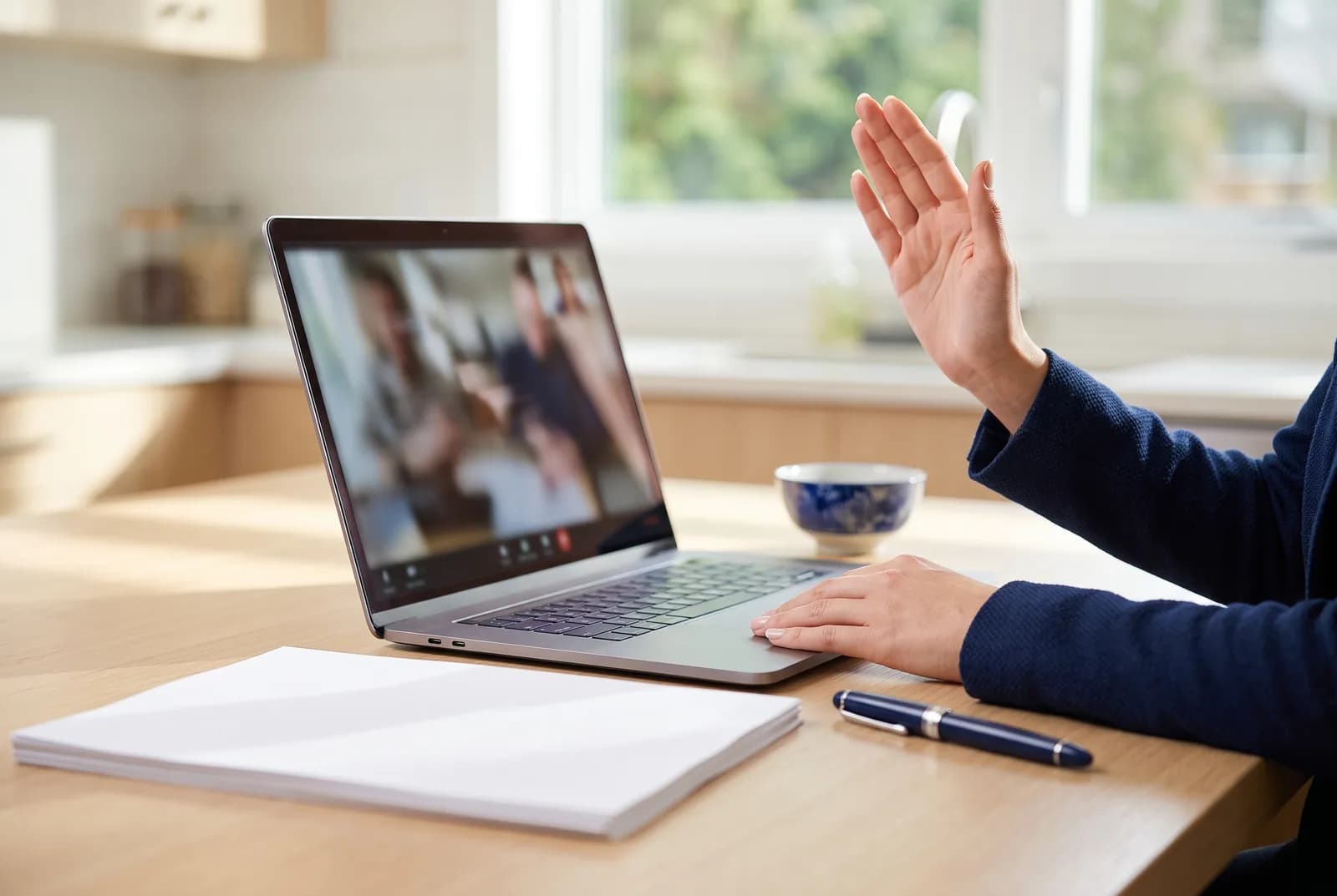 A person raises their hand to affirm an oath during a video call with a commissioner at their kitchen table