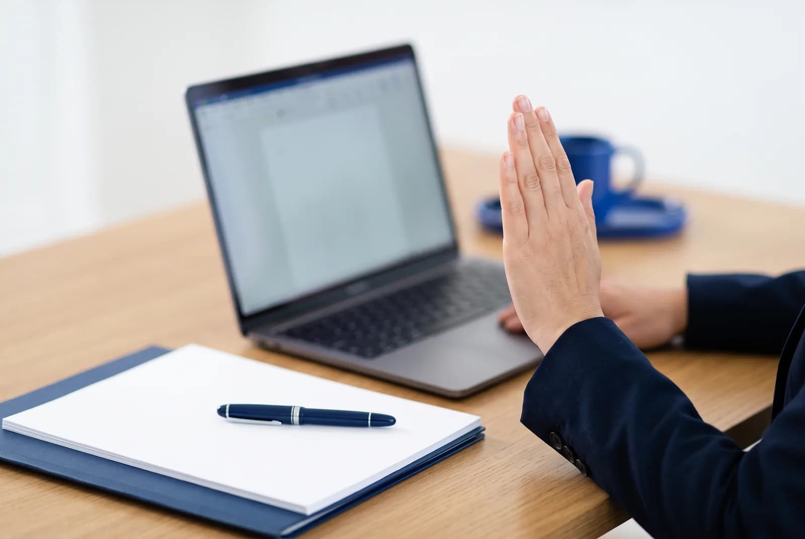 A hand raised in affirmation in front of a laptop showing a document